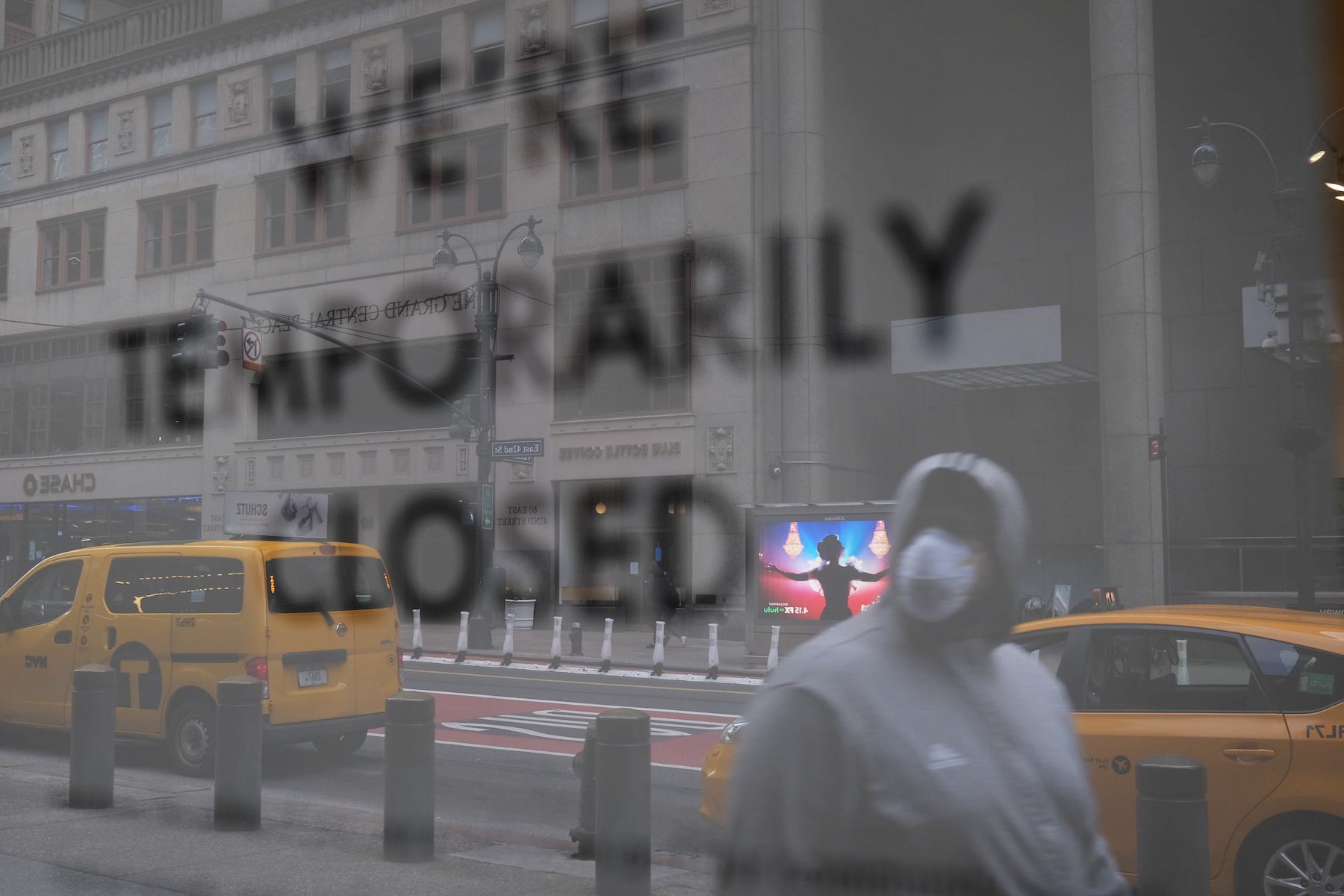 A man in a mask stands outside a building temporarily closed due to Covid-19.